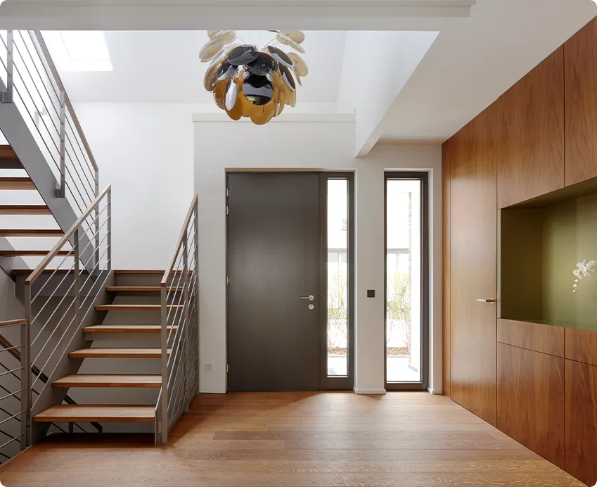 Modern entryway with a floating wood-and-steel staircase and light hardwood flooring
