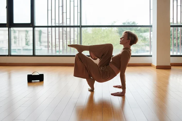 Woman holding a yoga pose on a sunlit hardwood floor