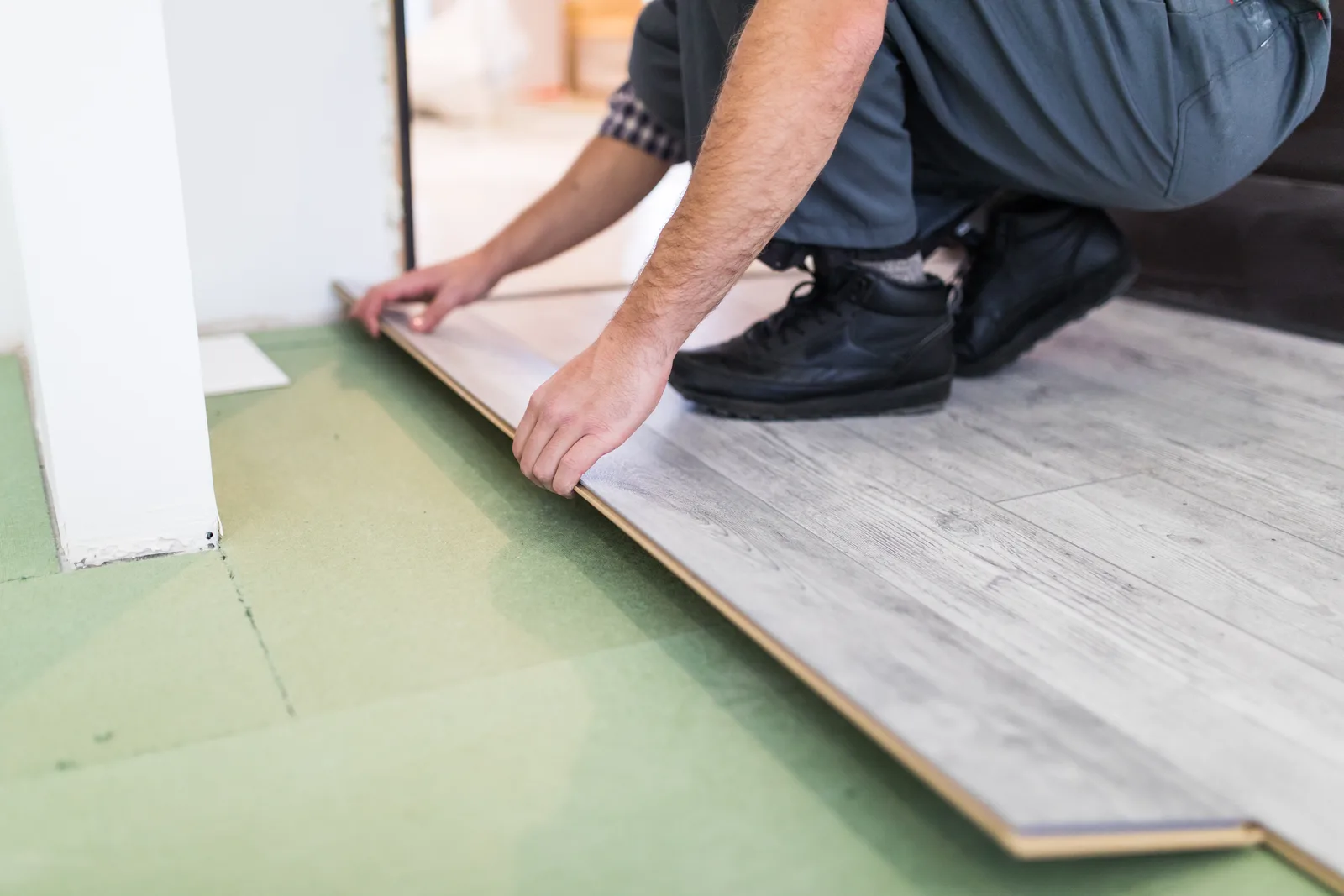 Installer fitting luxury vinyl plank flooring over fresh underlayment
