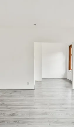 Empty white room with large windows and pale wood-look flooring