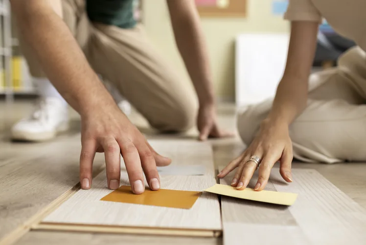 Hands measuring and cutting plank flooring on a worktable