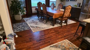 Dining room where dark hardwood meets tile, with area rugs