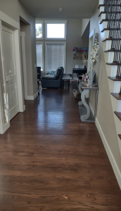 Hallway with dark hardwood flooring leading into a living room by AG Floor Covering
