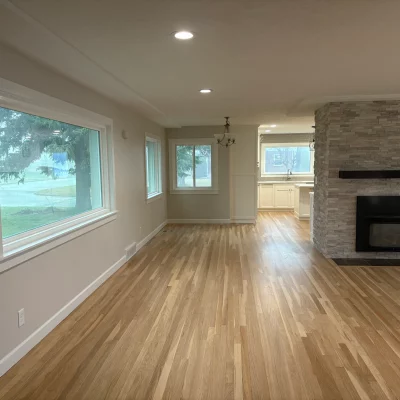 Living room with freshly finished light oak hardwood and a stone fireplace