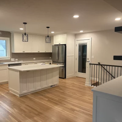 White kitchen with light oak hardwood flooring and a staircase landing