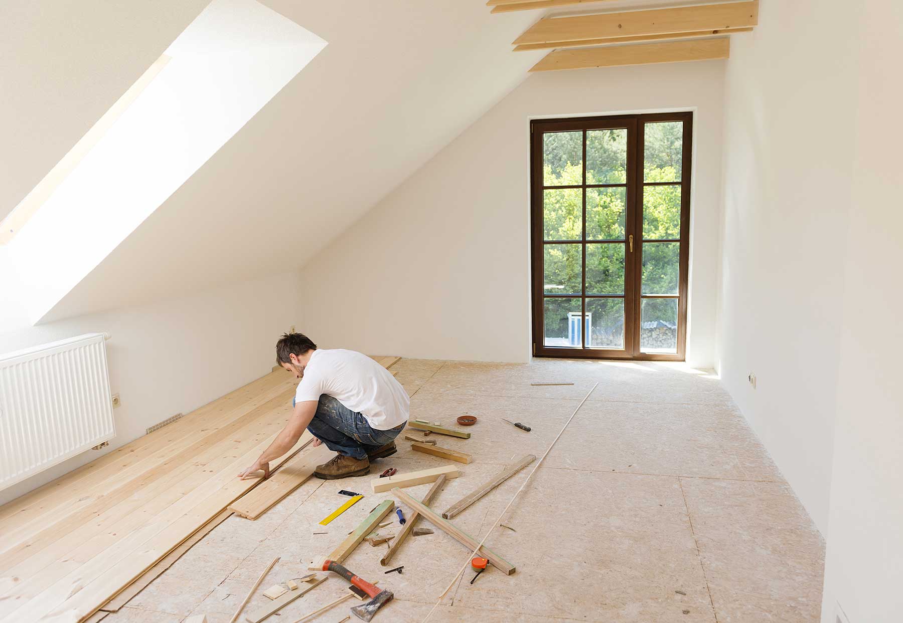 Worker in white shirt installing wooden floors