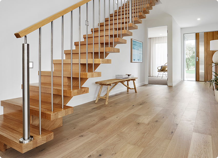 Modern wooden staircase that comes down to a hall with laminate flooring